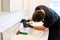 Man cleaning a bathroom sink with a scraper blade and micro fiber cloth to remove lime and stains