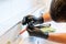 Man cleaning a bathroom sink with a scraper blade and micro fiber cloth to remove lime and stains