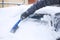 Man cleaning car from snow and ice with brush and scraper tool during snowfall. Winter emergency. Weather-related vehicle