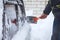 Man cleaning car from snow and ice with brush and scraper tool during snowfall. Winter emergency. Weather-related vehicle