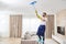 Man cleaning ceiling and lamps in living room. House cleaning service concept.