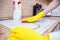 Man cleaning ceramic modern stove or hob with detergent agent. Hand in yellow gloves clean stove from burnt and grease dirt.