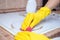 Man cleaning ceramic modern stove or hob with detergent agent. Hand in yellow gloves clean stove from burnt and grease dirt.