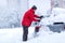 Man cleaning Frozen car covered snow at winter day