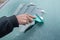 Man is cleaning frozen car window with ice scraper.