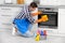 Man cleaning kitchen oven with rag