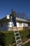 Man Cleaning Rain Gutters, Inspecting House Roof