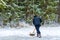 A man cleaning snow with a shovel. Clearing a skating or ice rink in the forest. Winter, fun, work, shoveling snow