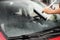 Man cleaning windshield with glass wiper, closeup