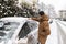 A man cleans a car of snow that has fallen overnight