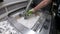 Man cleans details printed on an industrial 3D printer from white plastic powder