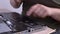 Man cleans dirt from laptop cooling fans system with silicone dust blower tool