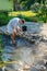 man cleans garden pond bottom with high-pressure washer from mud and sludge.