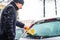 Man cleans his car from the snow