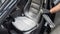 A man cleans leather car seats with foam.