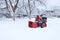 man cleans snow with snow blower