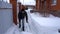 A man cleans snow in the winter in the courtyard of the house. A man cleans the snow with a shovel