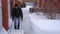 A man cleans snow in the winter in the courtyard of the house. A man cleans the snow with a shovel