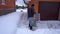 A man cleans snow in the winter in the courtyard of the house. A man cleans the snow with a shovel