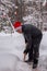 A man cleans steps from snow. In a red hat of Santa Claus and a leather black jacket. In felt boots. Clearing snow from the backya