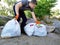 The man cleared the park and the beach from debris. He is holding bags of trash and plastic. The concept of teaching children to