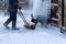 Man clears snow with a snow blower in house yard.