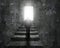 Man climbing concrete stairs toward door with bright light.