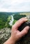 Man climbing on rock outdoor, close-up image of climber hand with river and nature in background