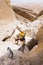 Man climbing stone desert gorge using iron steps stairs .