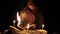 a man in a cloak with a hood is reading a hot book with candles on the floor