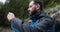 A man, close-up portrait, takes a photo of a landscape with a small camera