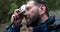 A man, close-up portrait, takes a photo of a landscape with a small camera