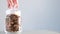 A man closes a jar of dried mushrooms on a gray background. Organically pure mushrooms collected