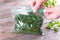 A man closes a plastic bag with frozen greens on a table