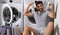 Man with clothes near washing machine. Handsome man sits in front of washing machine. Loads washer on laundry. Man