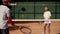 A man coach with a ward girl conduct a joint training tennis set at light intensity. The serving and deflecting blows
