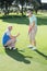 Man coaching his partner on the putting green