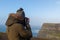 Man with a coat and hat taking pictures in a beautiful natural setting. Tourist on the cliffs of Moher in Ireland