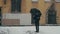 Man in coat with umbrella standing under snow holding plastic cup with hot drink