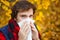 Man with cold rhinitis on autumn background. Fall flu season. Il