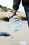 Man collects a used plastic bottle on the beach