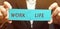 A man collects wooden puzzles with the words Work and Life. The concept of paying attention to the life values, promotion at work