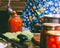 A man in a colored apron clogs tomatoes and Lecho sauce in glass jars in a farmhouse.