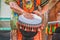 Man in colorful costume plays African ethnic percussion drum with tassels against blurred background - cropped and motion blur on