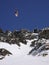 Man in colorful outfit skiiing down a very steep snow couloir under a cable car station in the Swiss Alps in deep winter