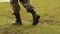 A man in combat boots walking on the green grass