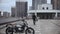 Man coming away from motorbike holding helmet on top of the multi-level parking