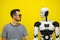Man communicates with a robot on a yellow background. man negotiates with artificial intelligence
