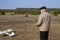 A man controls a radio-controlled aircraft on the field in early spring