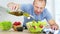 Man cook pouring olive oil into the fresh vegetable salad in his kitchen. Slow motion video shot on Black Magic Cinema